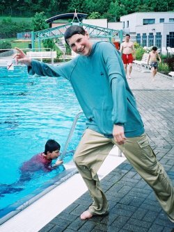 jumping into a pool in a hoodie
